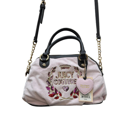 Pink handbag with 'Juicy Couture' branding on a wooden surface with a gray background